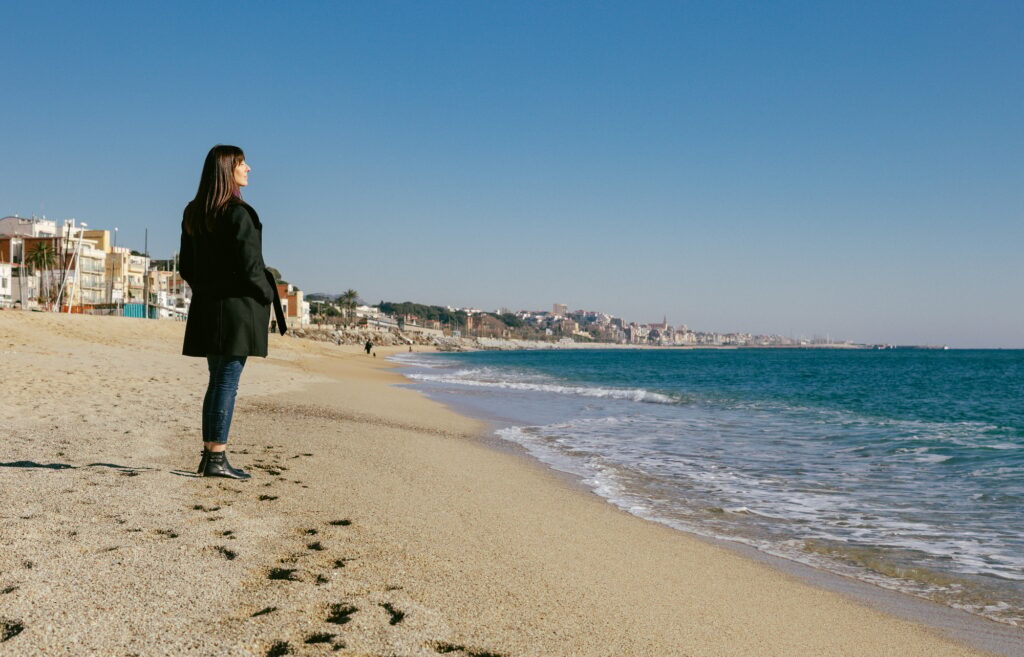 Woman standing on the beach looking at the sea