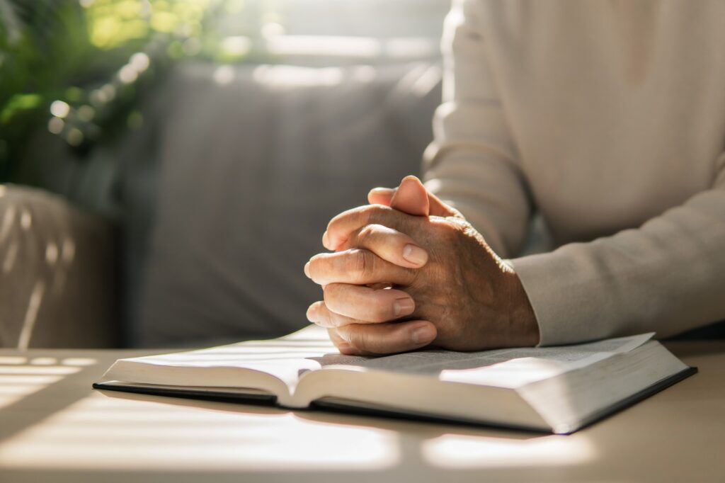 Women put their hands together and pray to God with the scriptures. Belief in God.